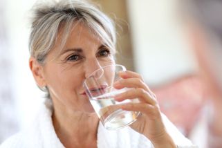 Une femme buvant de l'eau minérale naturelle dans un hôtel spa