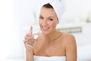 Femme en serviette de bain buvant de l'eau