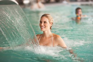 une femme sous un jet d'eau thermale dans une piscine